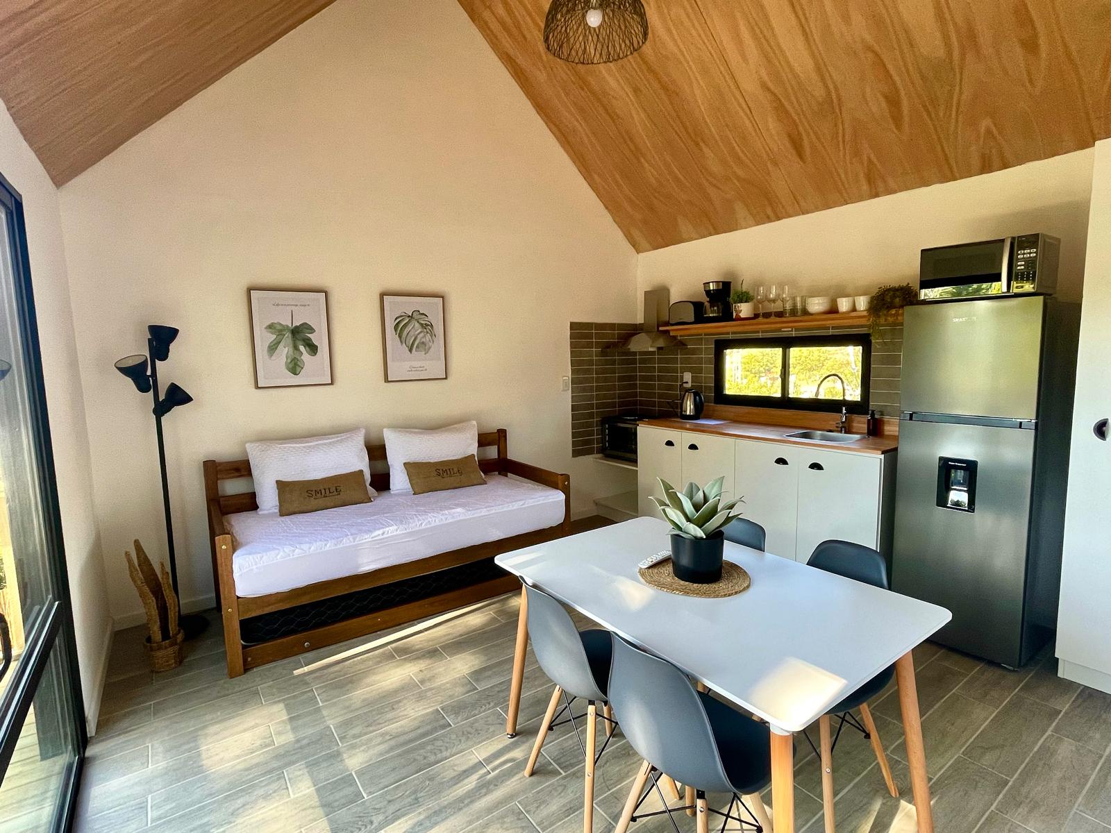 Estar de un bungalow con sofá cama, cocina y luz cálida