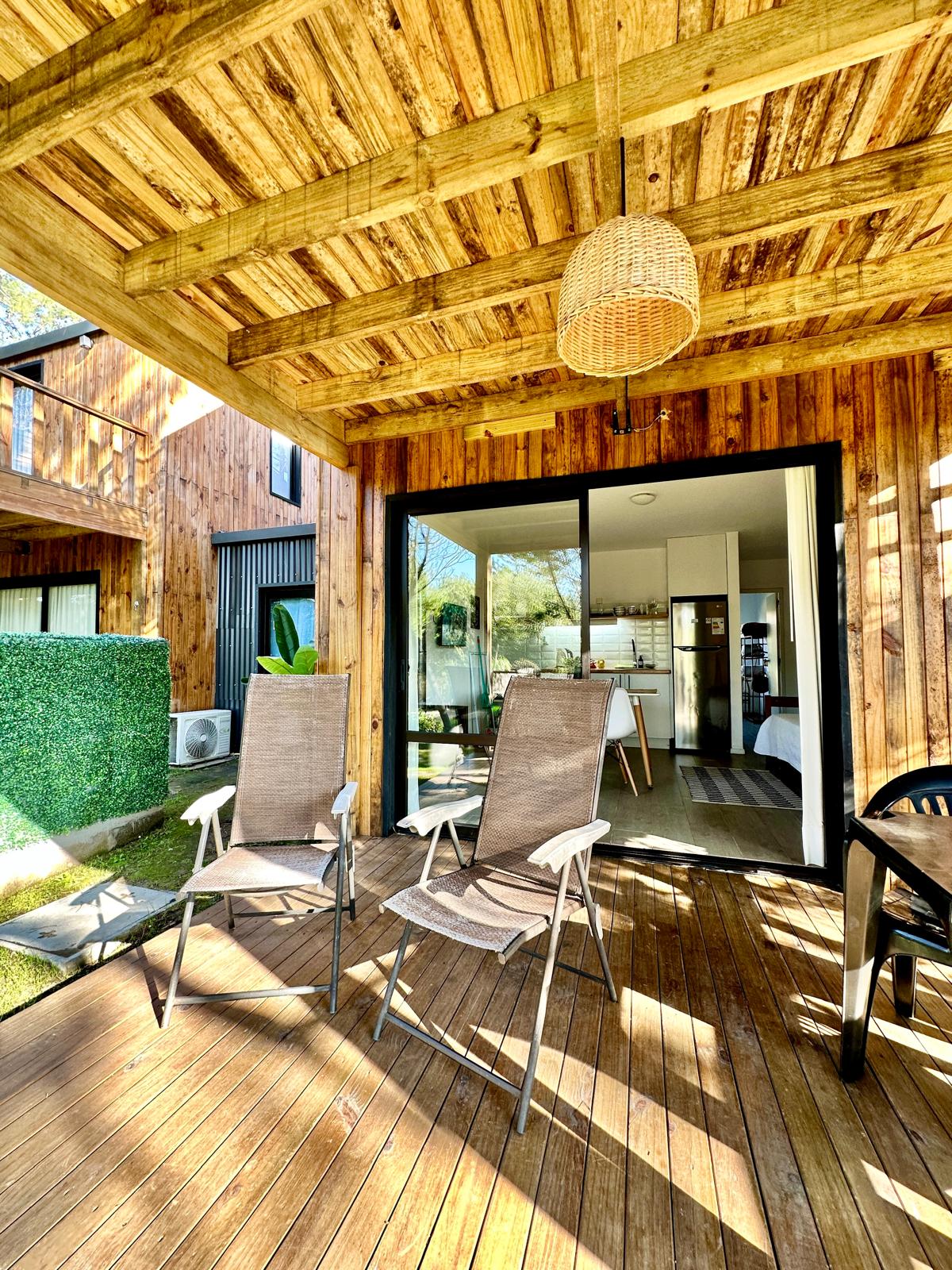 Galería de madera con sillas mirando el jardín